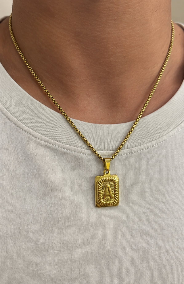 The Initial gold letter A pendant necklace on a box chain, worn with a white t-shirt